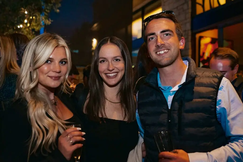 A group of young professionals posing and smiling together while enjoying drinks during a networking event at Ballast Point Brewing Company.